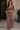 A woman models a matching two-piece lounge set made of a textured, velour-like fabric. The set includes a cropped long-sleeve top with a drawstring neckline and matching wide-leg pants.