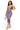 A woman models a strapless bodycon midi dress with a colorful tie-dye pattern in purple, pink, and blue. She is holding a beige rope handbag and wearing beige high-heeled sandals against a solid white background.
