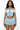 Woman wearing a light blue off-shoulder top and ruffled skirt with lace-up details on a white background.