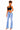 A woman modeling light-wash blue flare jeans with a black crop top, standing against a plain white background.