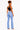 A woman shown from the back wearing light-wash blue flare jeans, a black crop top, and heels against a plain white studio background.