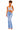 A woman modeling light-wash blue flare jeans with a gray ribbed crop top, standing against a plain white background.