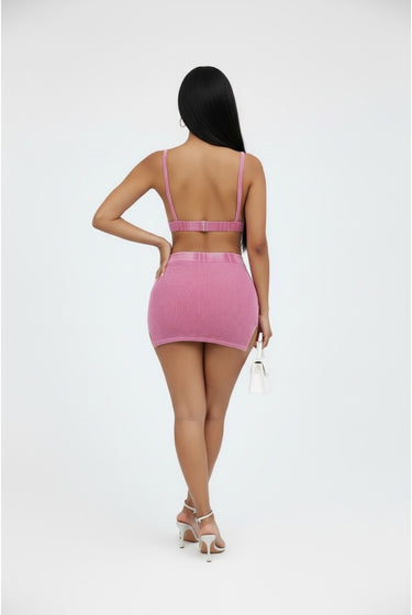 Person wearing a pink two-piece outfit on a white background