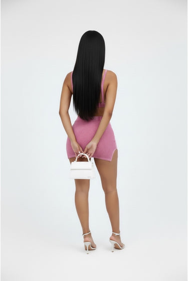 Person wearing a pink dress holding a white handbag on a white background